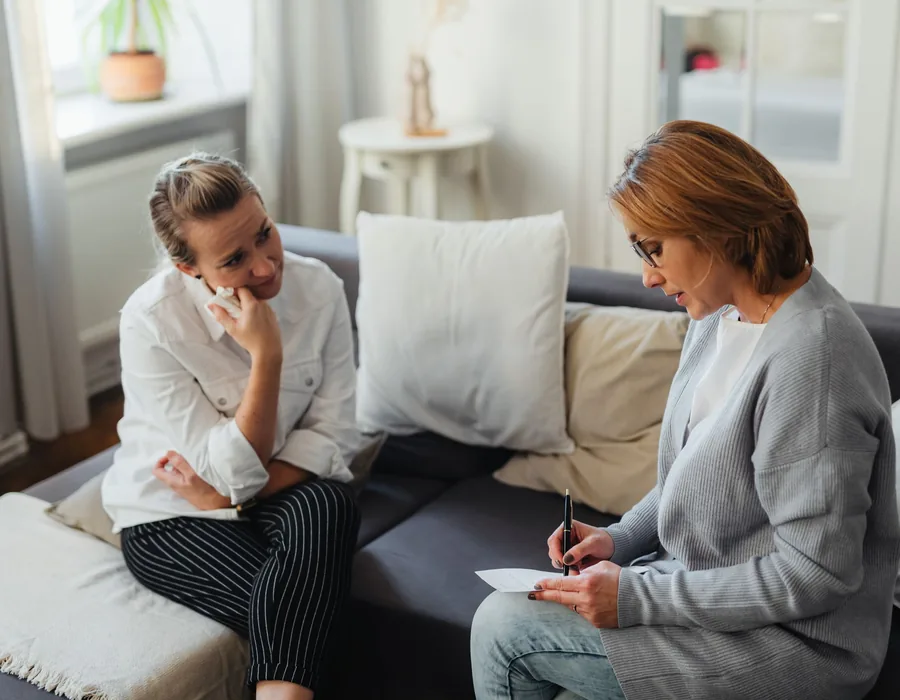 A psychologist talking with a mother on a sofa in the therapy room
