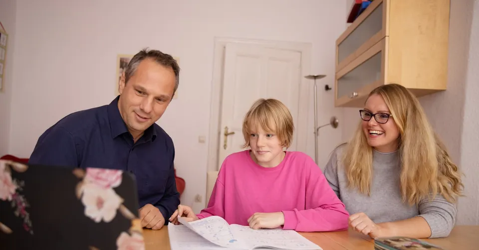 Rodzice odrabiają lekcje z córką przy stole